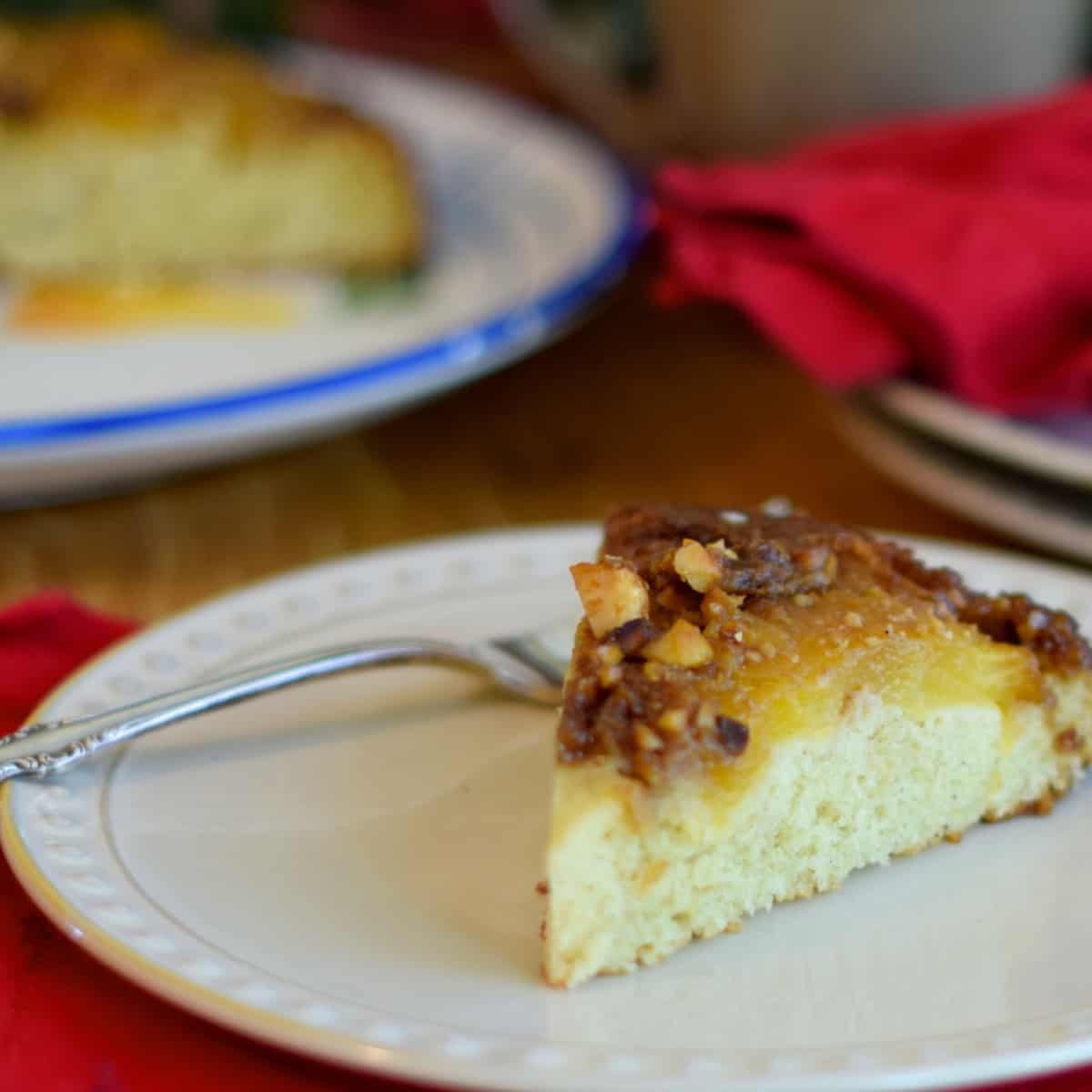 Bright red napkins highlight the slice of Pineapple Macadamia-Nut Upside-Down Cake on a beige plate. 