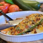 Zucchini boat in a white dish stuffed with tomatoes, corn, onions, and spices.