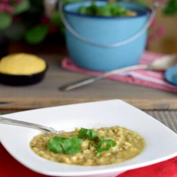 White bean chicken chili in a white bowl with cornbread in the background.