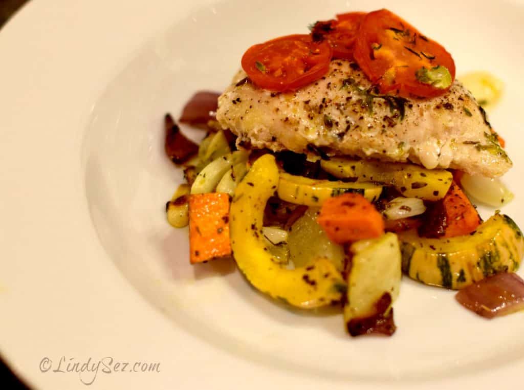 Oven poached chicken with roasted veggies in a white bowl.