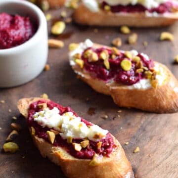 Roasted Beet Crostini with Goat Cheese and Pistachio on a wooden board.