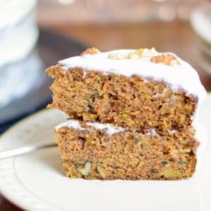A slice of Super Moist Carrot Cake with Creamy Frosting on a white plate.