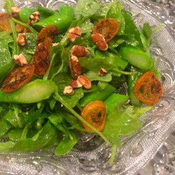 Caramelized Kumquat and Arugula Salad in a glass antique bowl.