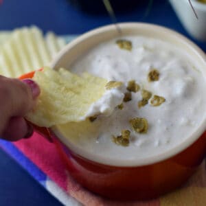 A ruffle cut chip being used to enjoy a bite of retro clam dip.
