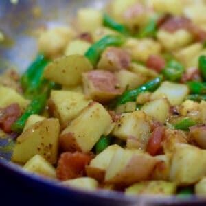 Curried Potatoes combines with green beans in a large saute pan.