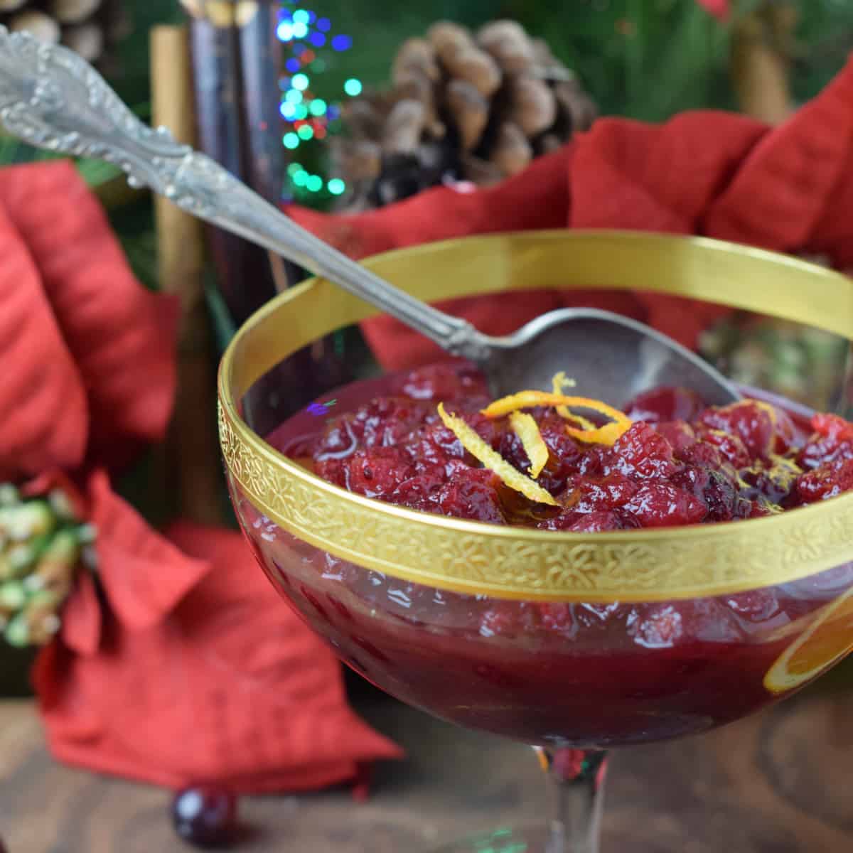 Christmas colors and a gold rimmed glass bowl hightlight Quick Fresh Cranberry Orange Sauce.