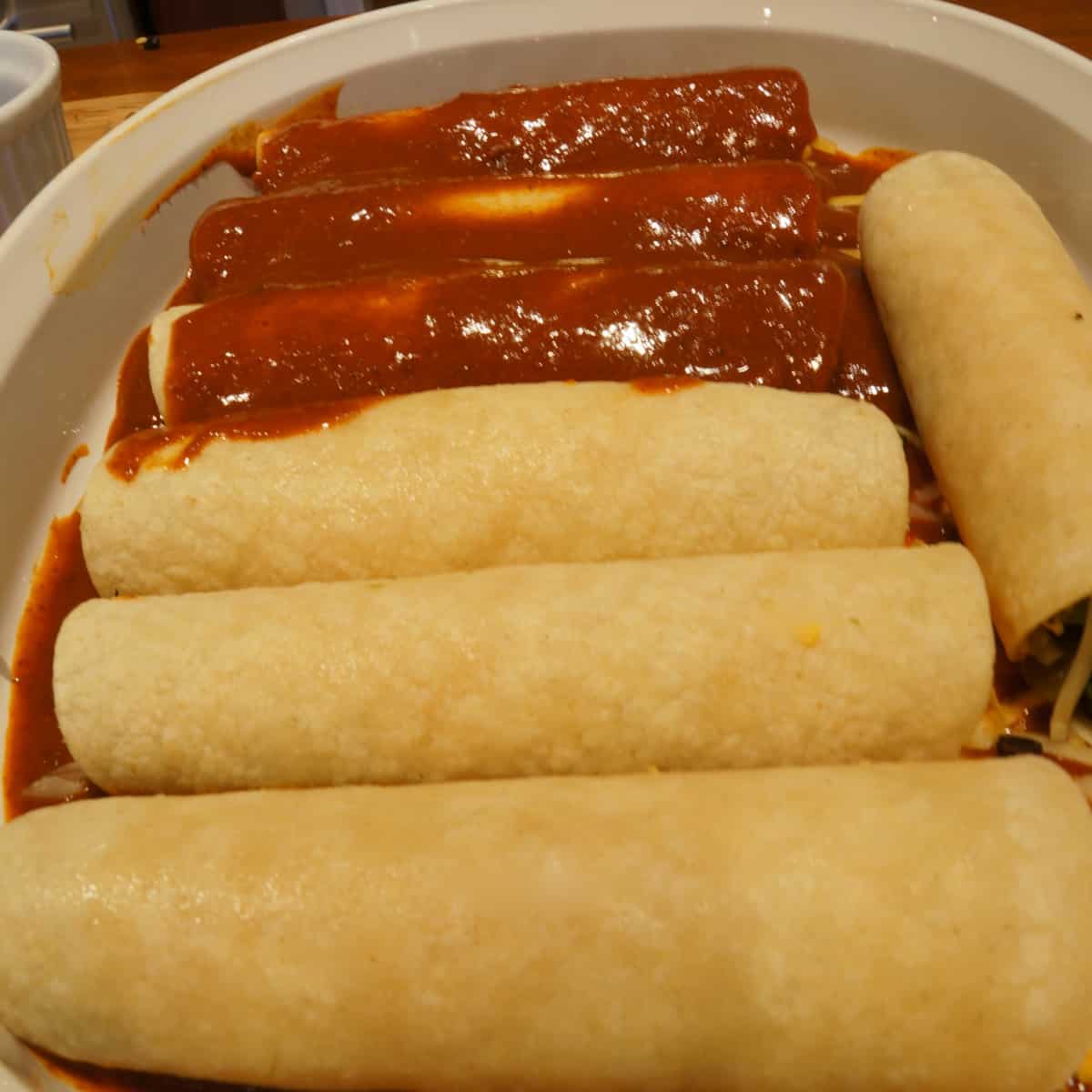 Building the best fully loaded cheese enchilada with red sauce.