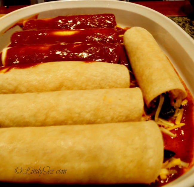saucing a fully loaded cheese enchilada