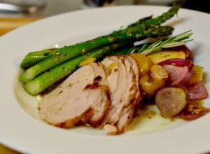 Roasted Pork Loin with Apples and Onions on a plate with grilled asparagus