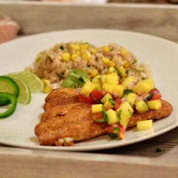 A plate of Simple Panfried Curry Snapper with Mango Salsa with brown rice.