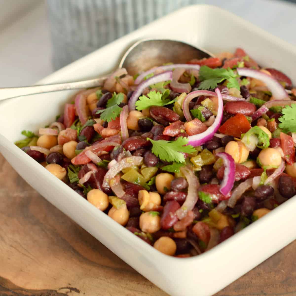 A white square bowl with Mexican spicy 3-bean salad in it.