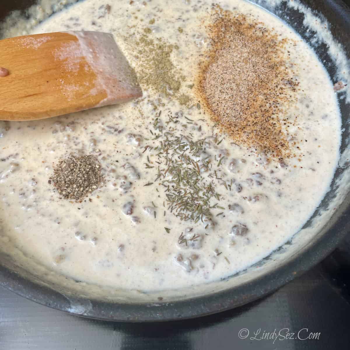 Spices being added to sausage gravy.