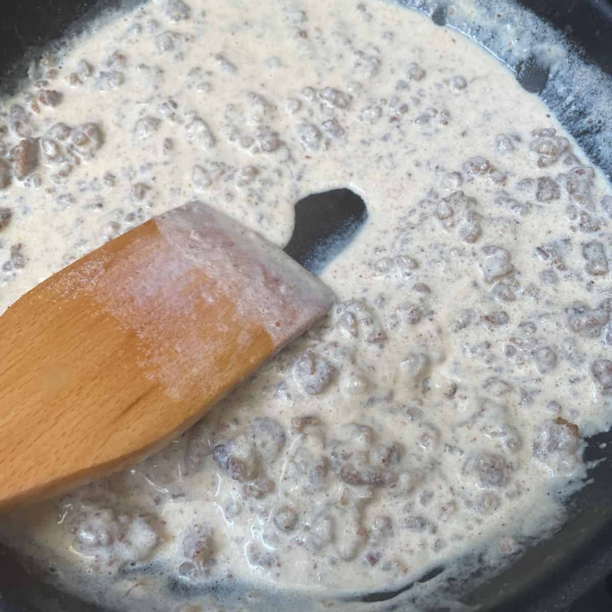 Running a spoon through a flour gravy to show how thick it is. 
