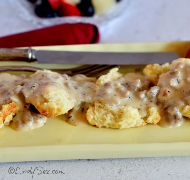 A plate of simple savory sausage gravy on biscuits on a yellow plate.
