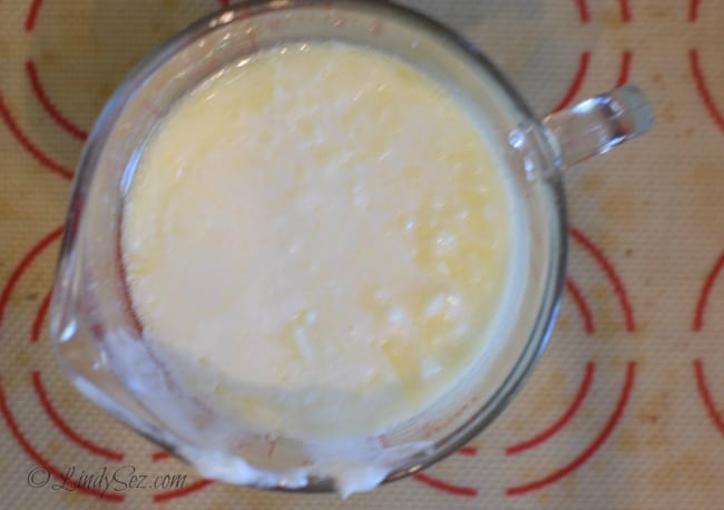 A view of the butter and buttermilk combined in a glass to be used in tender homemade buttermilk biscuits.