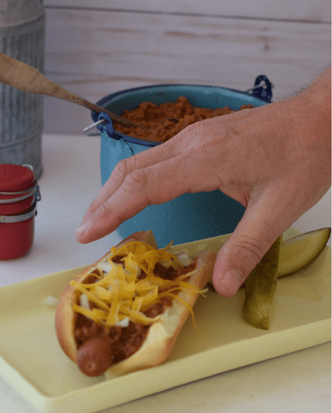 A hand making a grab for a tasty chili dog made with my Hormel Chili no beans copycat recipe.