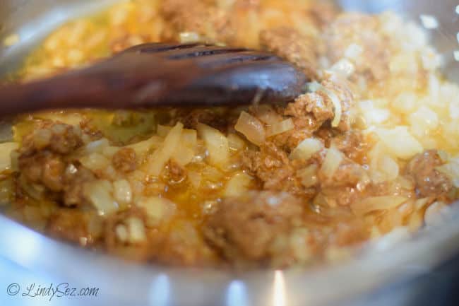 Onions and chorizo cooking together in a saucepan.