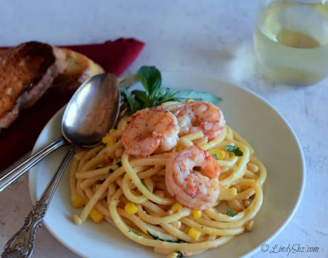 An overhead shot of Shrimp on Bucatini with Pine Nuts and a glass of wine.