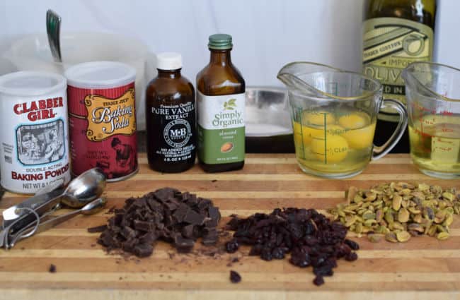 A cutting board showing the ingredients for Chocolate Cherry Biscotti with Pistachio.