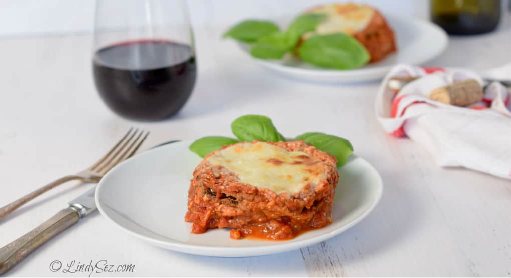 Two plates of Easy Low-Fat Baked Eggplant Parmesan with basil garnishes.