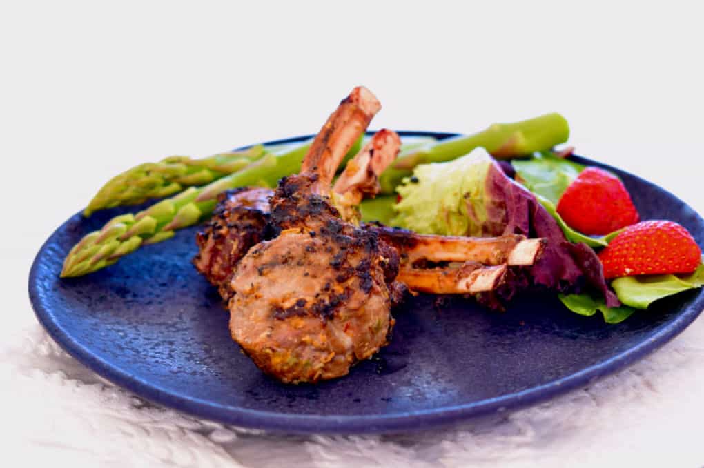 Lemongrass Grilled Lamb chops on a blue plate with fresh asparagus.
