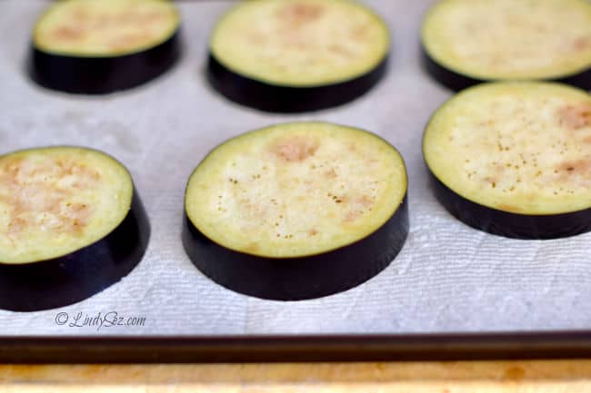 A baking sheet with slices of eggplant that have been salted.