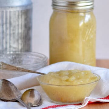 A bowl of chunky homemade apple sauce with some in a jar for saving.