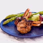 Grilled lamb chops and bright green asparagus on a blue plate.