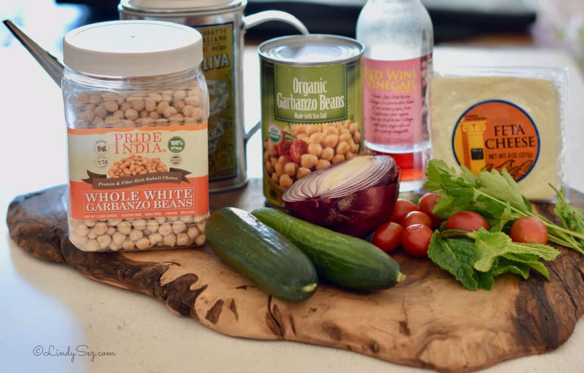 The ingredients for Mediterranean Chickpea Salad on a rustic wooden board.