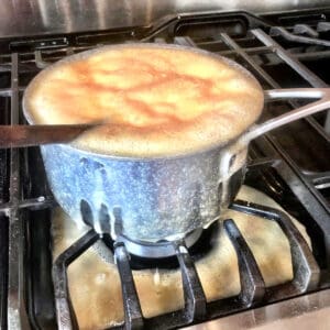 The mixture of milk and sugar boiling over onto the stove.