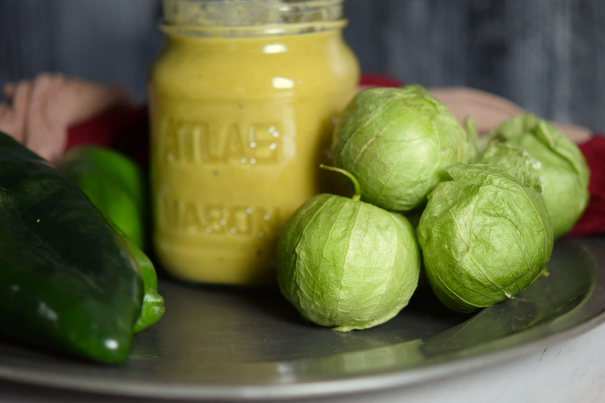 Green sauce in a jar with tomatillos.