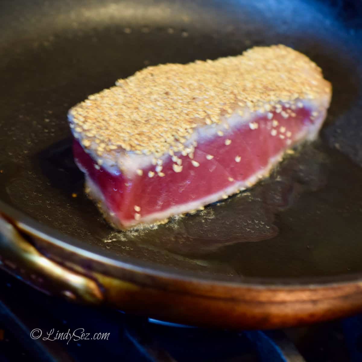 Sesame crusted ahi tuna being seared in a hot skillet.