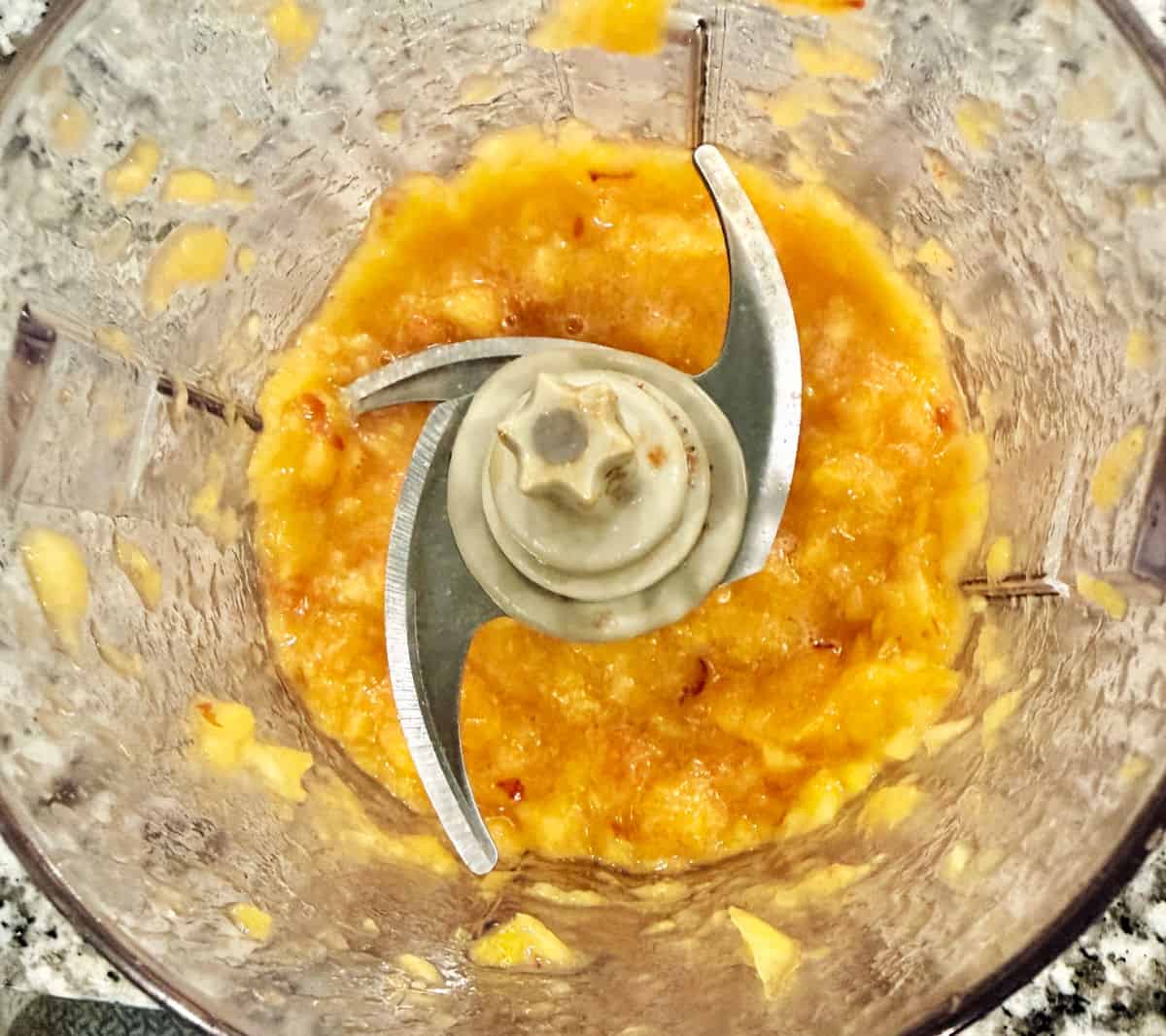 An overhead view of fresh peach puree in a mini food processor.