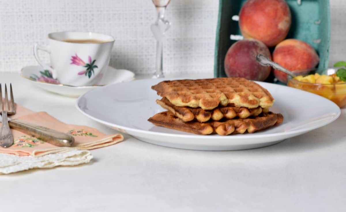 Peach waffles on a plate with peaches. 