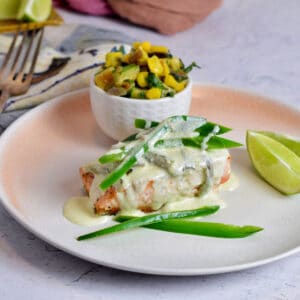 Ready to serve salmon with jalapeno cream sauce on a pink plate.