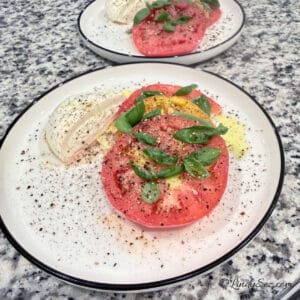A Burrata Caprese Salad on a white plate.