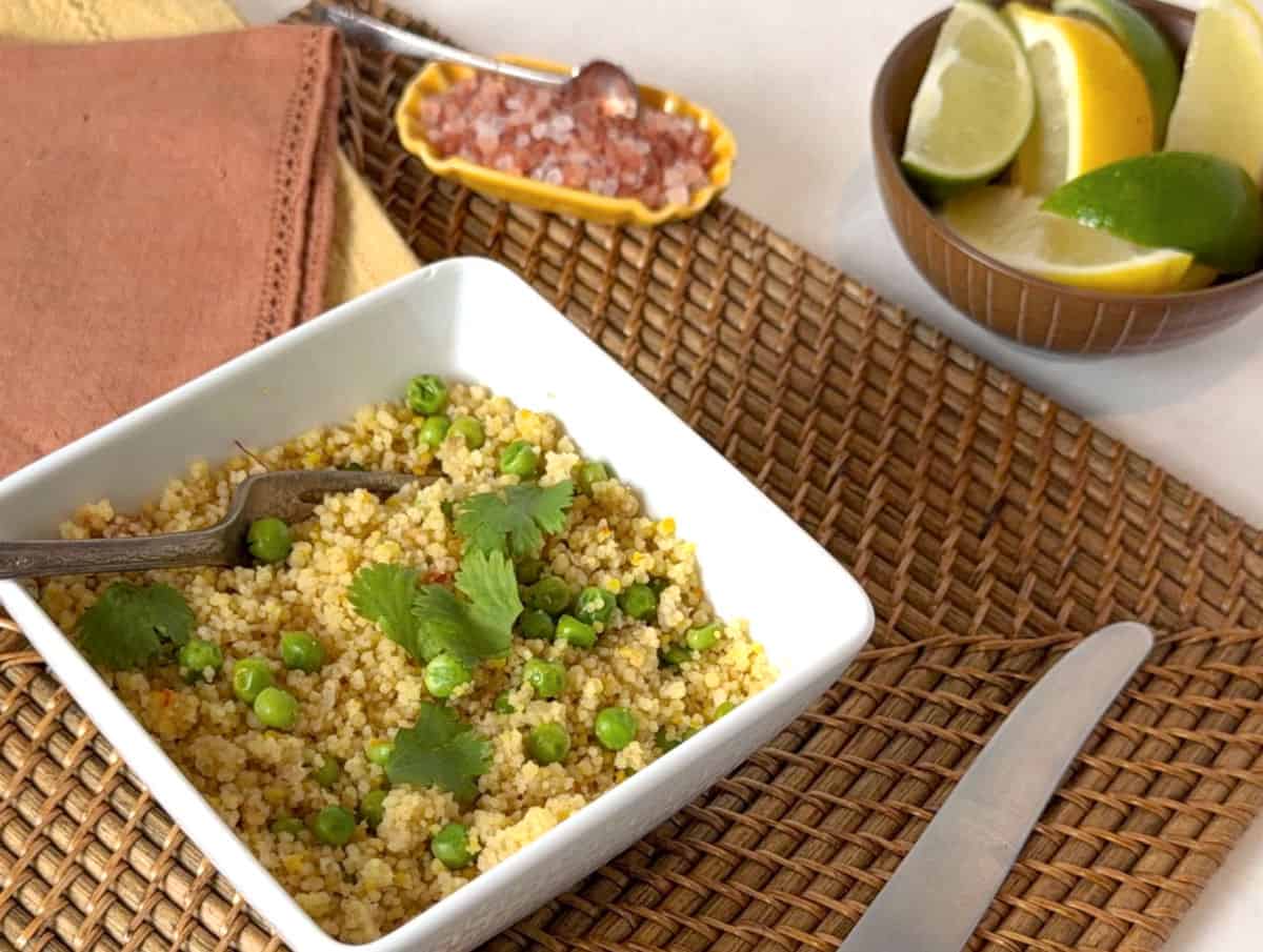Toastedcouscous in a white square bowl with citrus.
