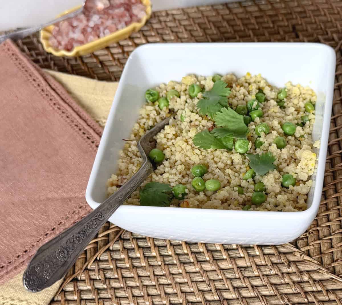 A bolw of toasted couscous with golden onions and peas.
