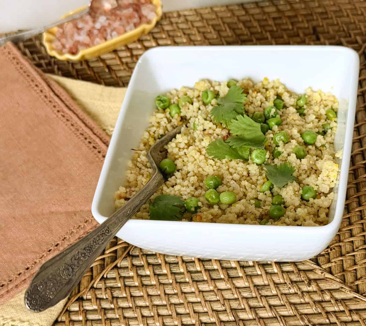 A dish of couscous with peas and cillantro.