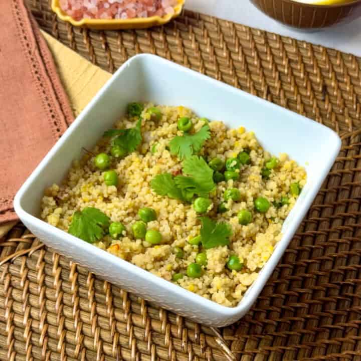 A close up of a square bowl with couscous and peas in it.