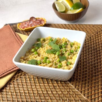 A square white bowl with golden couscous in it.