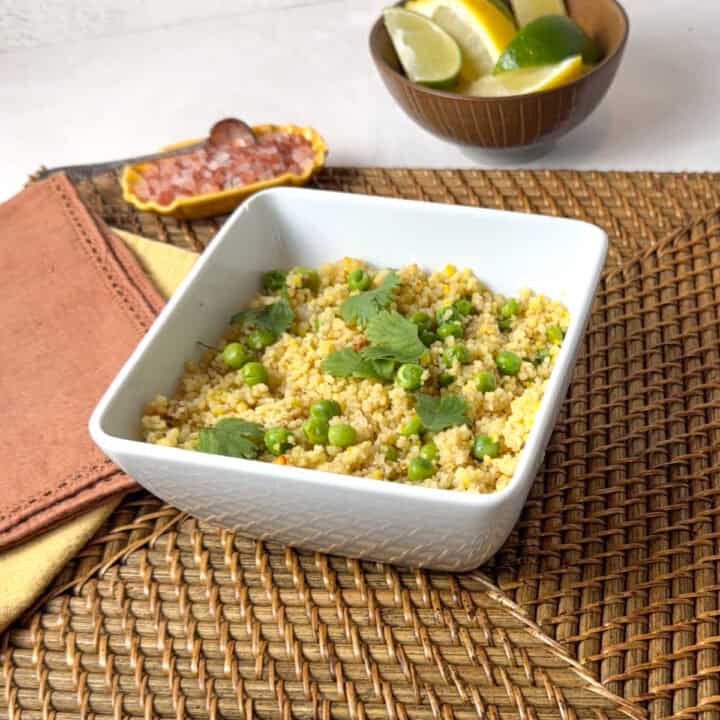 A square white bowl with golden couscous in it.